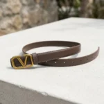Brown Valentino Garavani VLogo thin leather belt with antique brass buckle on a stone pedestal (5)