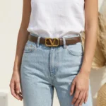 Brown Valentino Garavani VLogo thin leather belt with antique brass buckle on a stone pedestal (6)