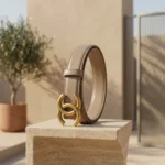 Slim womens taupe leather belt featuring an antique gold interlocking buckle on a stone pedestal (2)