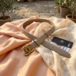 Slim womens taupe leather belt featuring an antique gold interlocking buckle on a stone pedestal (5)