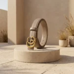 Womens Gucci Double G leather belt in taupe with antique brass hardware on a stone pedestal (1)