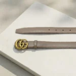 Womens Gucci Double G leather belt in taupe with antique brass hardware on a stone pedestal (2)