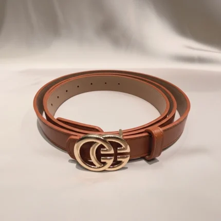 a rolled tan womens belt with a large gold interlocking buckle on a stone pedestal (1)