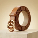 a rolled tan womens belt with a large gold interlocking buckle on a stone pedestal (2)